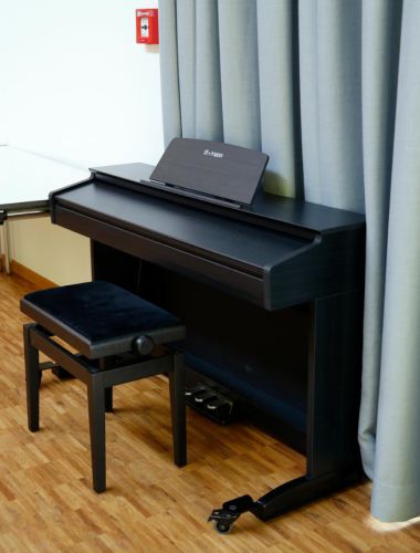 Großes, schwarzes Stand-E-Piano vor blaugrauem Vorhang
