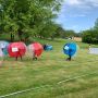 Mehrere Kids in Bubble-Soccer-Bumper-Balls auf dem Spielfelden während eines Spiels